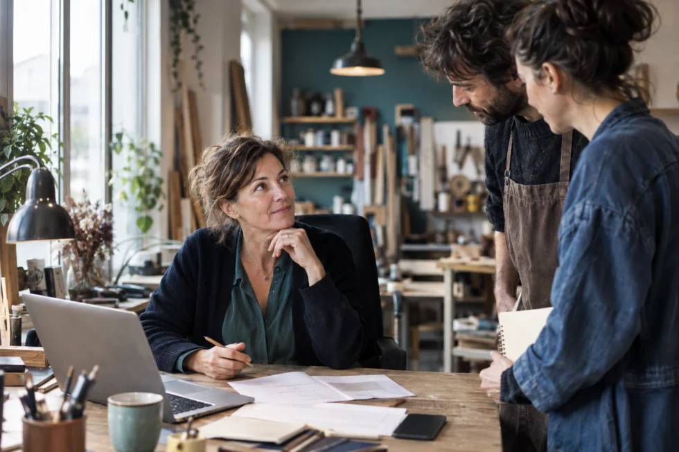 Scène illustrative : une dirigeante à son bureau, sollicitée par ses collègues