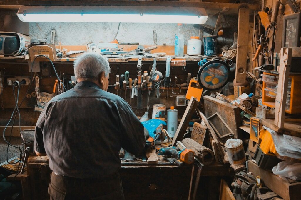 Artisan devant les outils et pièces de son atelier.