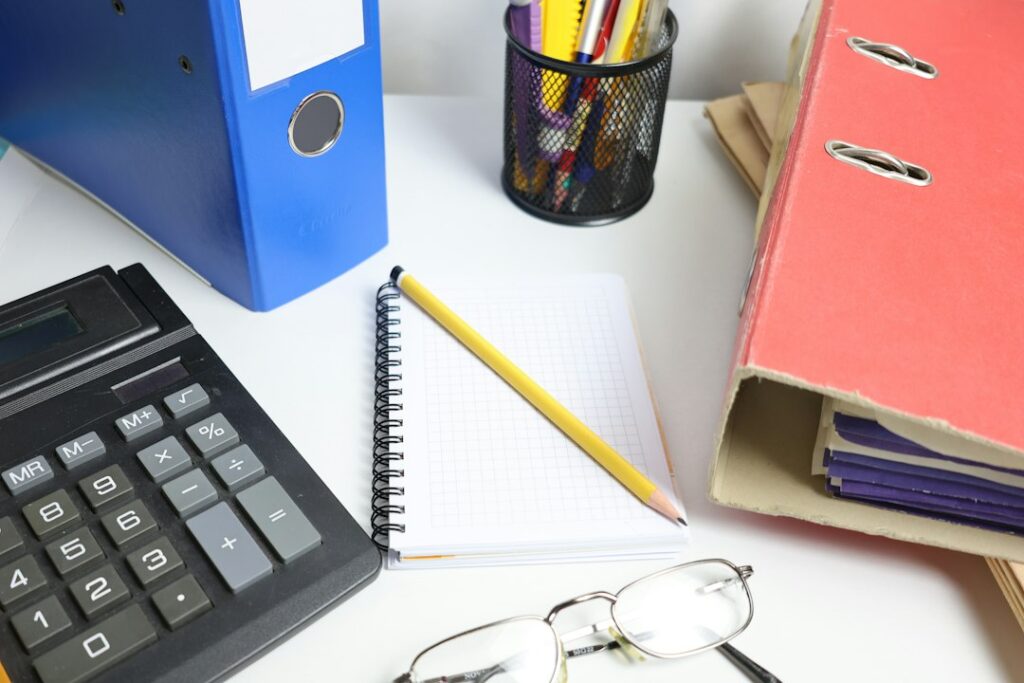 Illustration : documents de gestion et calculatrice sur un bureau clair.