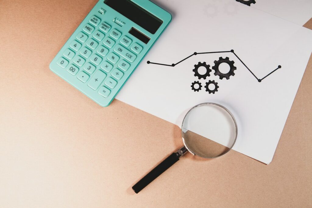 Calculatrice et loupe près d’un schéma de fonctionnement sur papier.