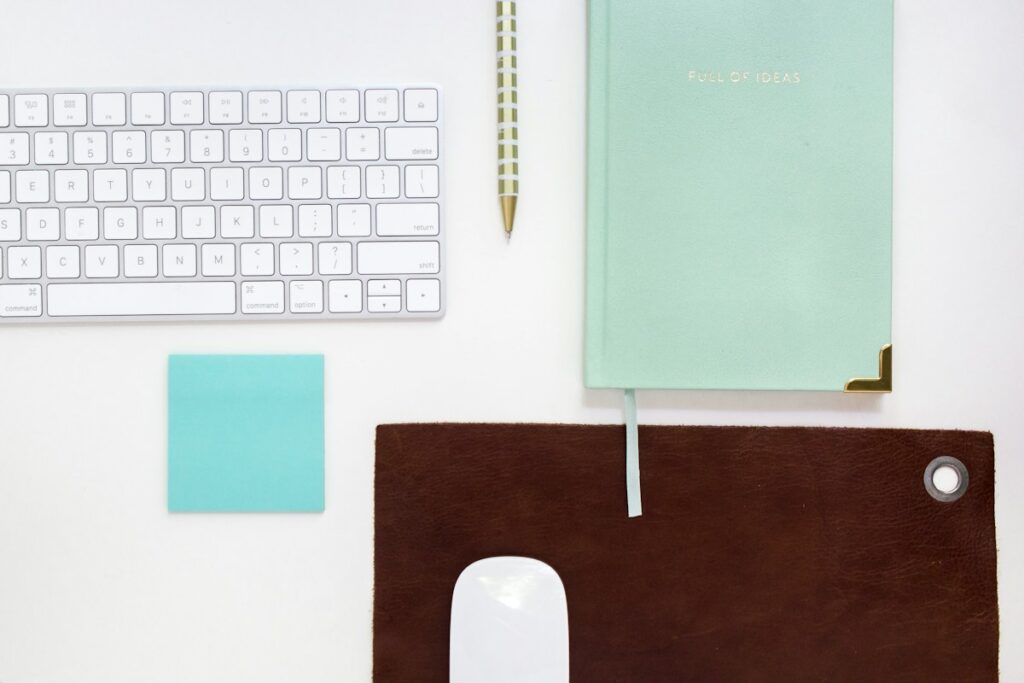 Clavier, carnet et fournitures de bureau sur un fond blanc.
