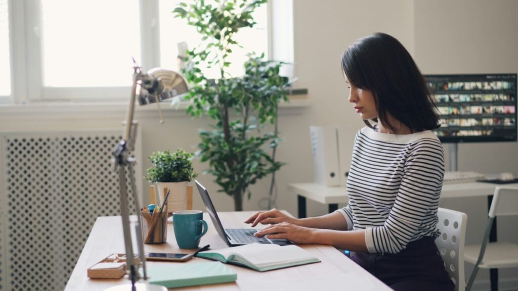 Personne travaillant sur ordinateur dans un bureau lumineux.