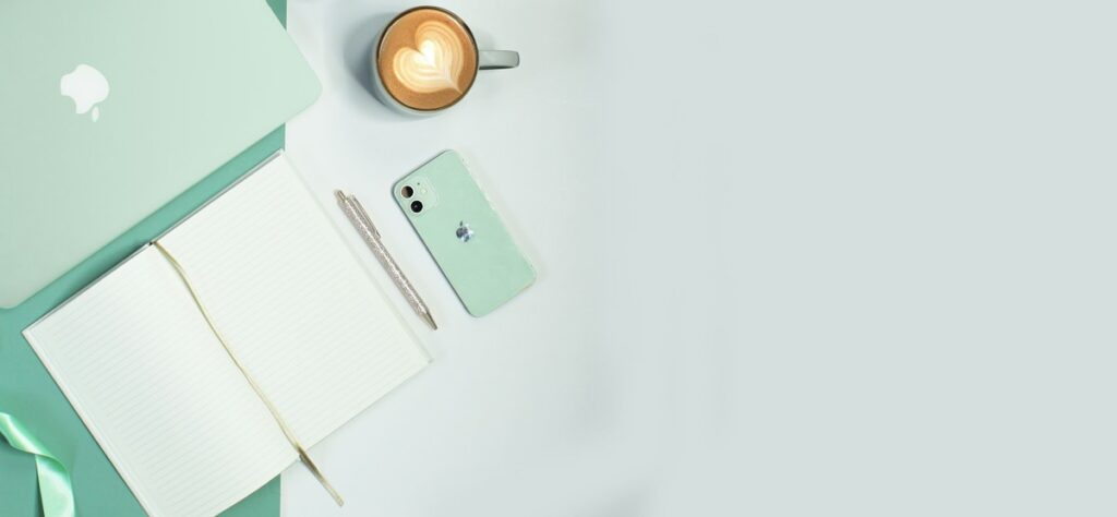 Carnet, téléphone et tasse sur un bureau clair.