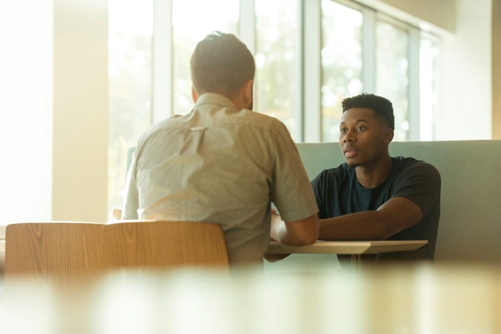 Échange professionnel dans un bureau éclairé par de grandes fenêtres.