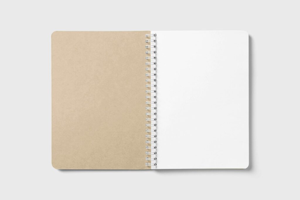 Carnet à spirale ouvert sur une page blanche, sur un fond clair.