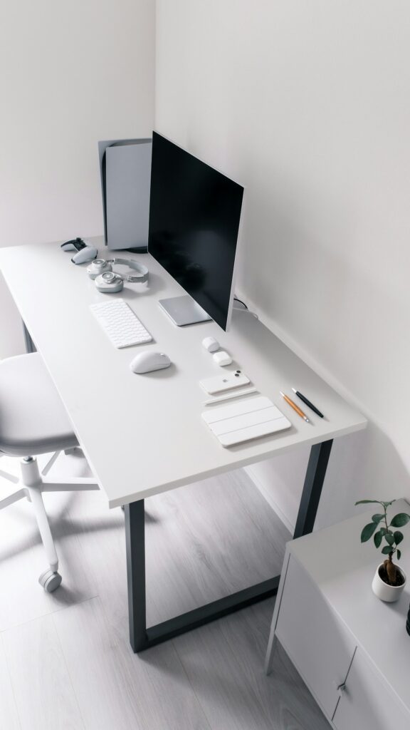 Ordinateur et accessoires sur un bureau blanc.