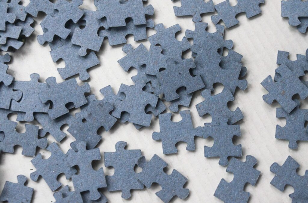 Pièces de puzzle gris bleu réparties sur une surface claire.