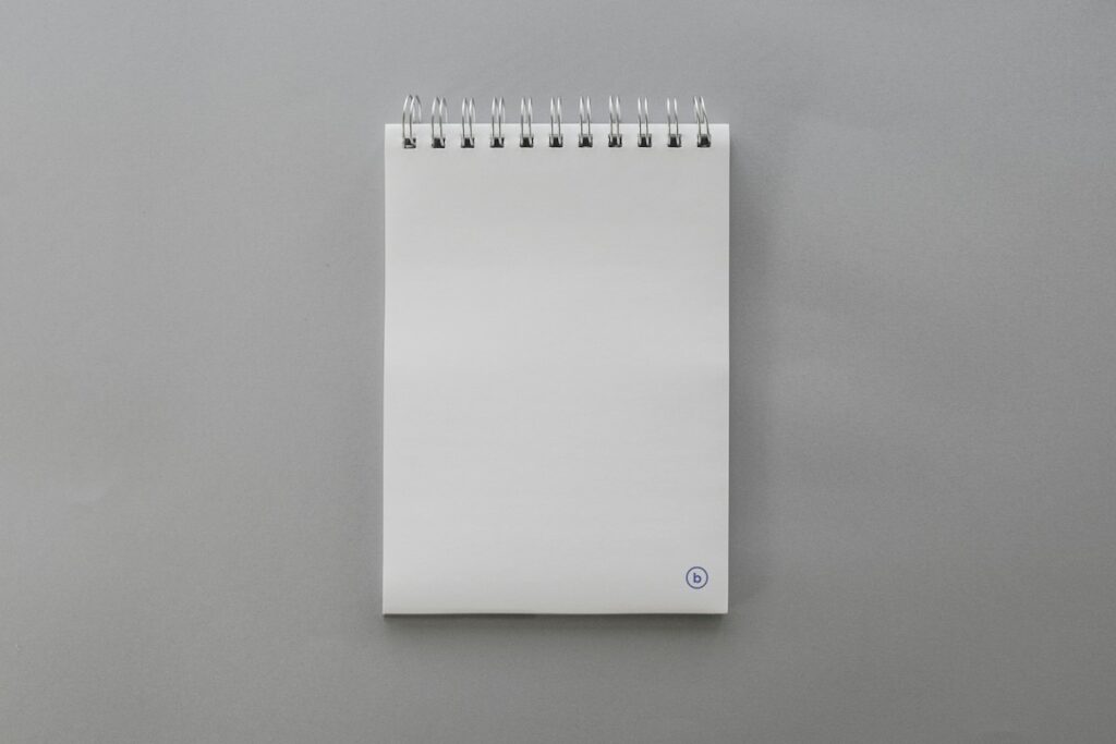 Bloc-notes à spirale vierge posé sur un fond gris clair.