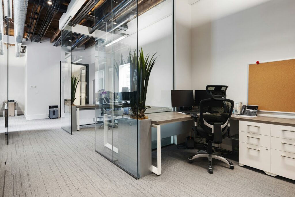 Espace de travail clair avec bureaux et cloisons vitrées.