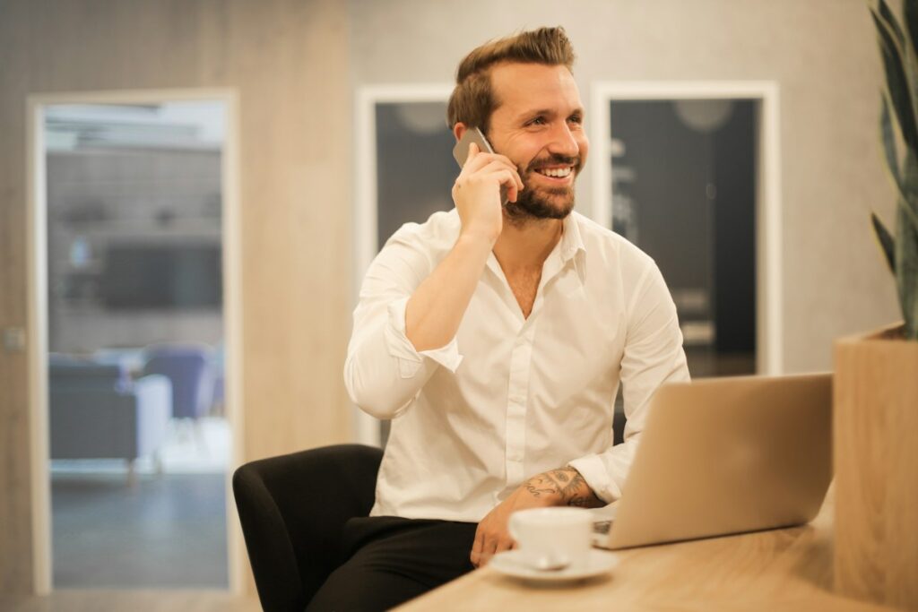 Professionnel au téléphone devant son ordinateur dans un bureau clair.