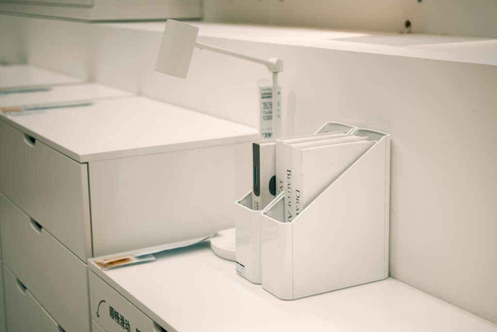 Rangement de bureau blanc contenant une règle et de petits documents.