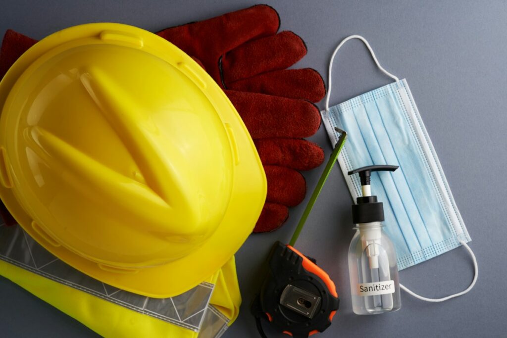 Casque de sécurité, gants et masque sur un support clair.