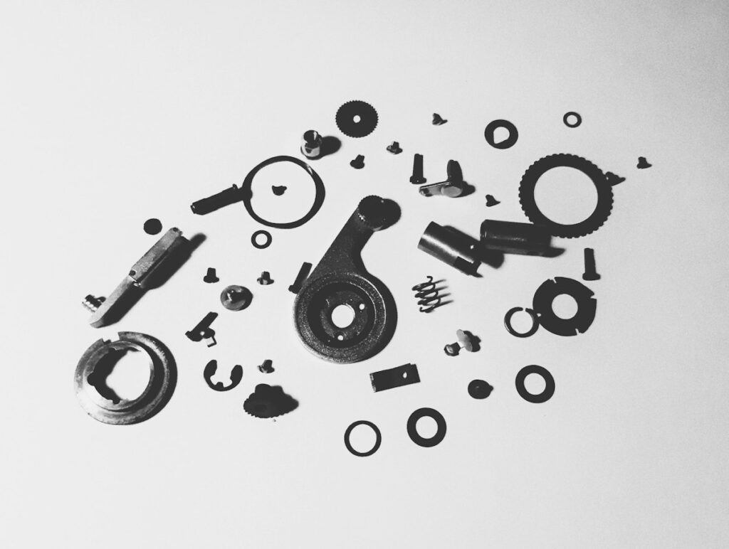 Pièces mécaniques, ressorts et rondelles répartis sur fond blanc.